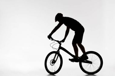 silhouette of trial biker in helmet balancing on bicycle on white clipart