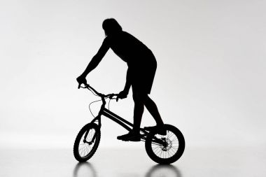 silhouette of trial biker balancing on bicycle on white clipart