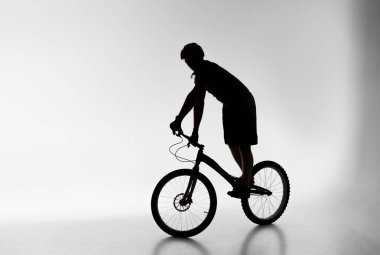 Beyaz Bisiklet üzerinde Dengeleme kask içinde deneme bisikletçi silüeti