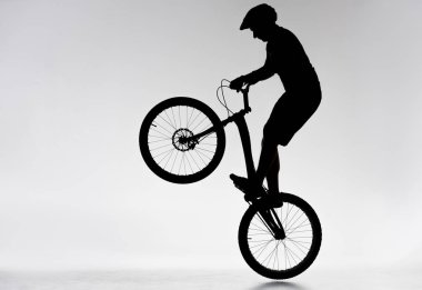 silhouette of trial biker performing bunny hop on white clipart