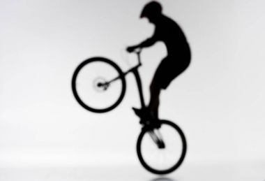blurred shot of silhouette of trial biker performing bunny hop on white clipart