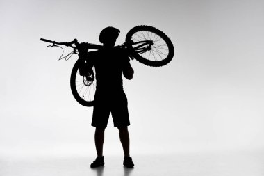 silhouette of trial biker holding bicycle on shoulders on white clipart