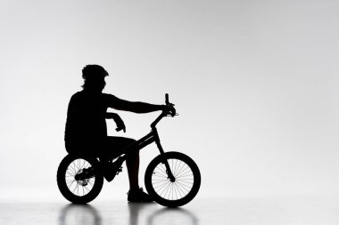 silhouette of trial biker relaxing on bicycle on white clipart