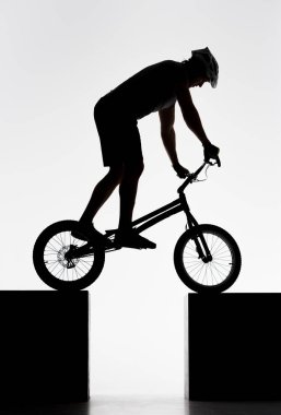silhouette of trial cyclist balancing on two stands on white clipart