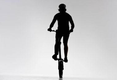 silhouette of trial biker riding on back wheel on white clipart