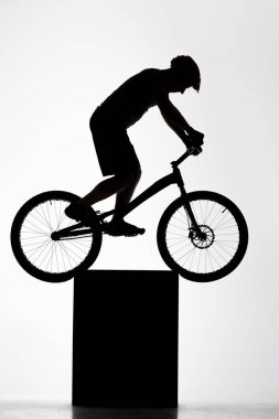 silhouette of trial cyclist balancing on stand on white clipart