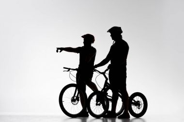 silhouettes of trial cyclists with bicycles chatting on white clipart