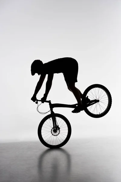 Silhouette Von Trial Biker Führt Vorderradständer Auf Weiß — kostenloses Stockfoto