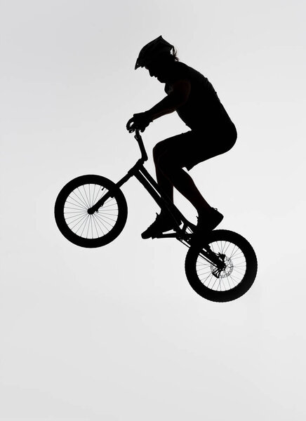 silhouette of trial biker jumping on bicycle on white