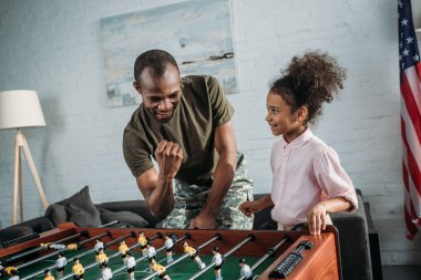 Asker baba ve Afro-Amerikan kızı masa futbolu oynayan mutlu aile