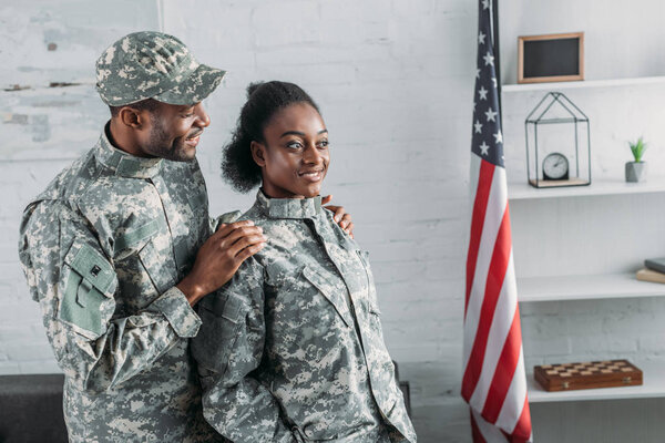 African american male soldier embracing woman in camouflage clothes