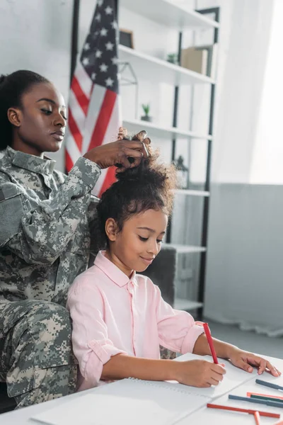 African American Female Soldier Fixing Hairstyle Daughter Busy Drawing Table — Stock Photo, Image