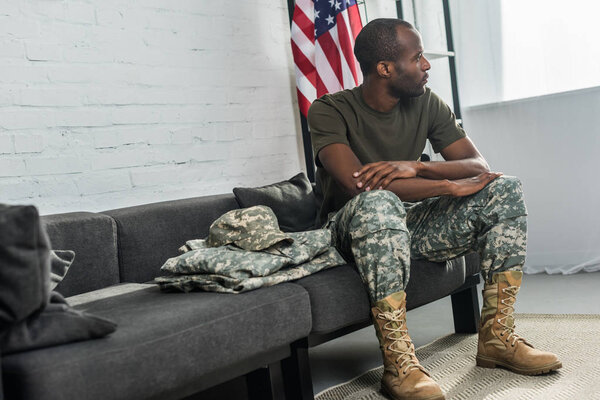 Handsome male soldier sitting on sofa with camouflage clothes