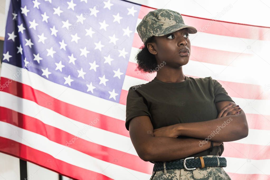 Female african american army soldier in camouflage clothes in front of us flag