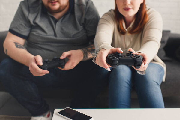 cropped image of boyfriend and girlfriend playing video game at home