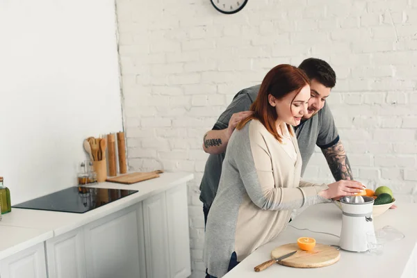 Sobrepeso Namorado Abraçando Namorada Enquanto Ela Fazendo Suco Cozinha — Fotografia de Stock