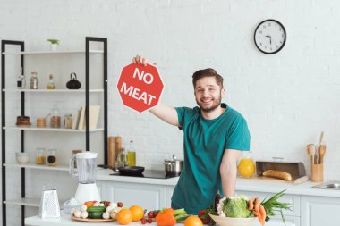 handsome vegan man showing no meat sign in kitchen clipart