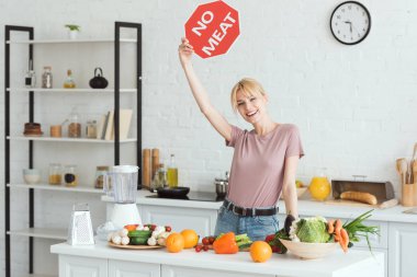 attractive vegan girl showing no meat sign in kitchen clipart