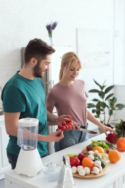 smiling couple of vegans cooking at kitchen clipart