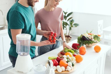 cropped image of couple of vegans cutting vegetables at kitchen clipart