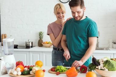 vegan boyfriend cutting vegetables at kitchen clipart