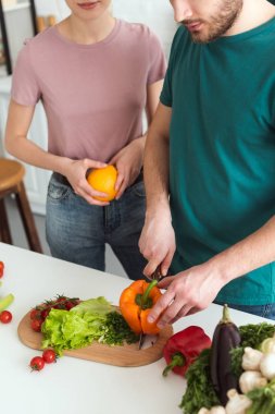 cropped image of boyfriend cutting vegetables for vegan salad at kitchen clipart