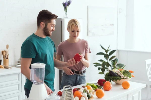 Ζευγάρι Των Vegans Βλέπει Κόκκινο Πιπέρι Κουδουνιών Στην Κουζίνα — Φωτογραφία Αρχείου