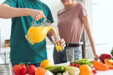 cropped image of vegan boyfriend pouring fresh juice into glass in kitchen clipart