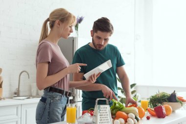 Tablet reçete ile mutfak, vegan kavramı pişirme sırasında işaret eden kız