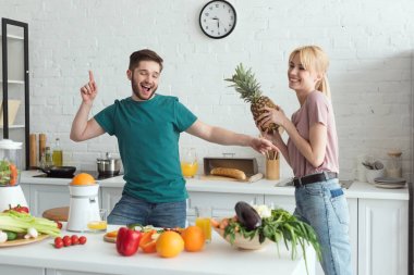 smiling couple of vegans having fun while cooking at kitchen clipart