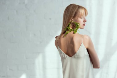 back view of young woman in dress with earring made of fresh arugula, vegan lifestyle concept clipart
