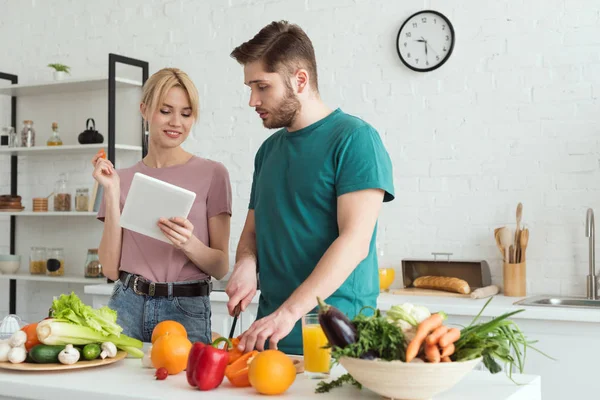 couple of vegans using tablet with recipe for cooking at kitchen