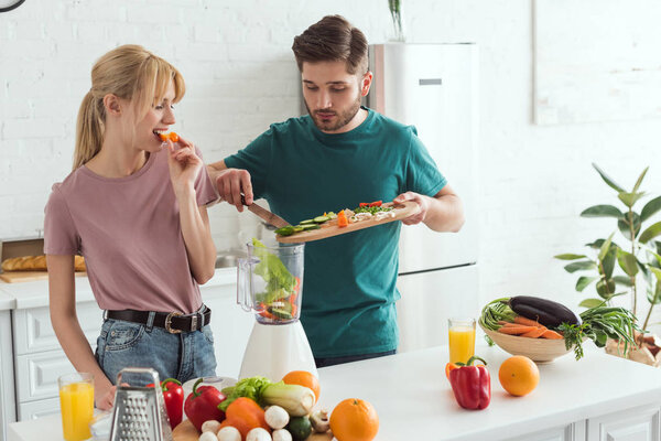 young couple of vegans preparing vegetable juice at kitchen