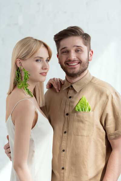 woman with earring made of arugula and boyfriend with savoy cabbage leaf in pocket, vegan lifestyle concept