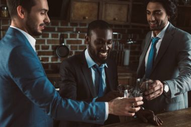 viski bardakları tokuşturup takım elbiseli genç çok ırklı erkek arkadaşlar gülümseyen