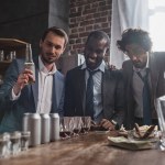 Jovens empresários multiétnicos que bebem bebidas alcoólicas juntos