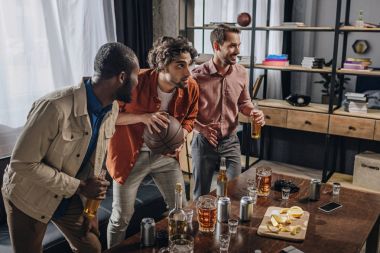 side view of multiethnic men playing with basketball ball and drinking beer together  clipart