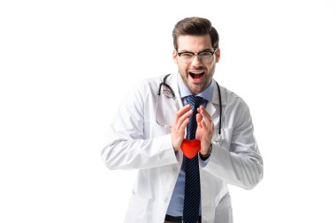 Neşeli doktor stetoskop ile beyaz ceket giyiyor ve üzerinde beyaz izole oyuncak kalp tutan