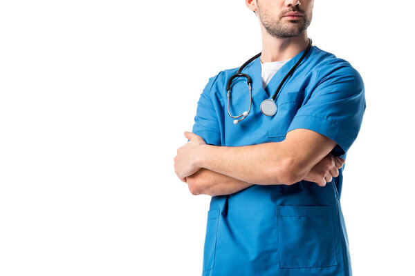 Close-up view of male nurse wearing blue uniform with stethoscope standing with folded arms isolated on white
