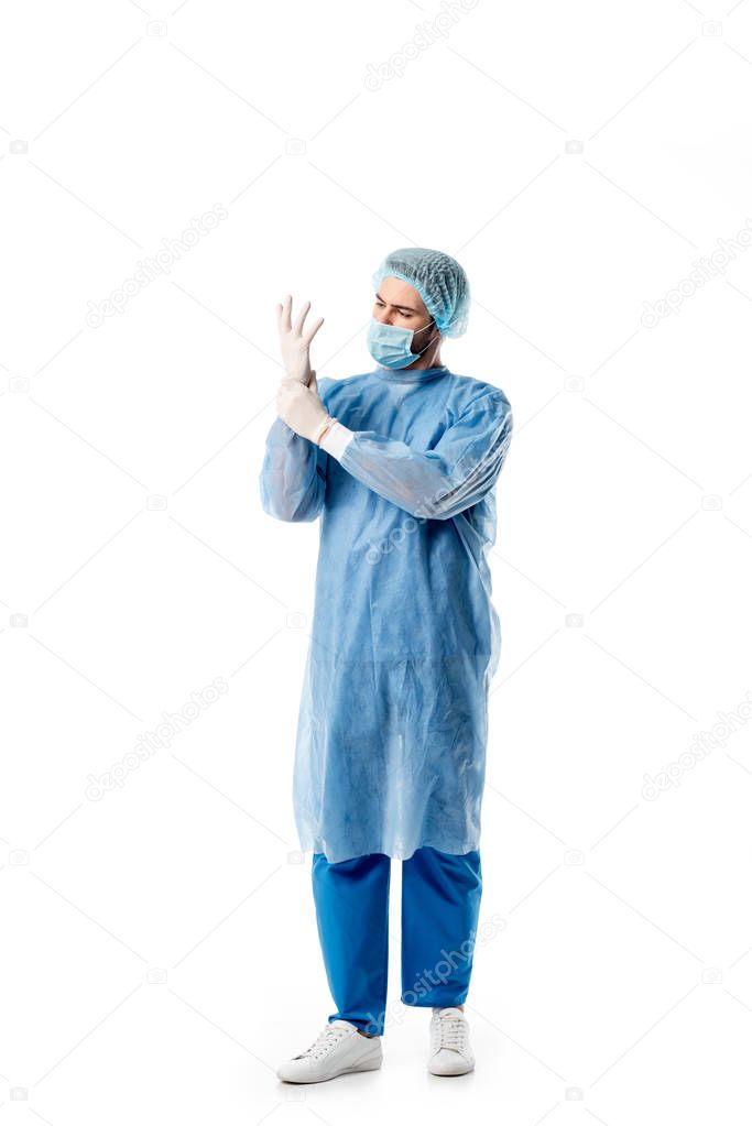 Surgeon in blue uniform wearing medical gloves isolated on white