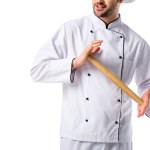 Cropped shot of chef in uniform with wooden rolling pin isolated on white