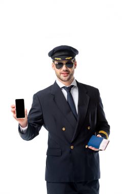 pasaport ve bilet el ile üzerine beyaz izole boş perde smartphone gösterilen üniformalı pilot portresi