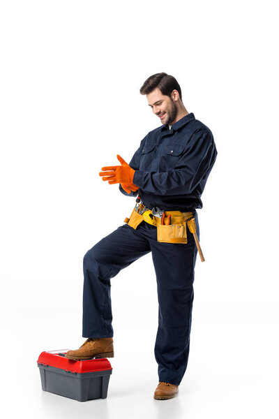 smiling plumber in uniform wearing protective gloves isolated on white