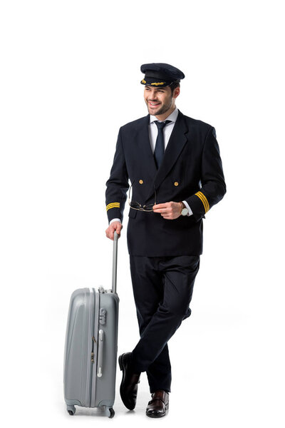 smiling pilot in uniform with luggage isolated on white
