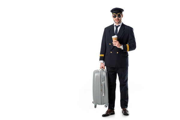 young pilot in uniform and sunglasses with coffee to go and luggage isolated on white