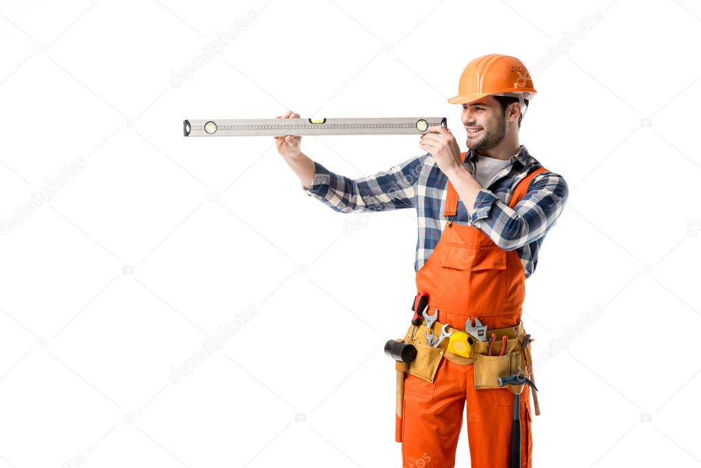 Young repairman in orange overall checking spirit level isolated on white