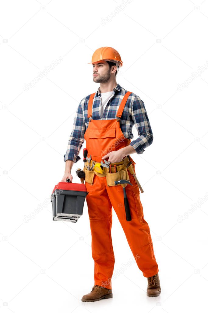 Young confident repairman in orange overall holding tool box isolated on white