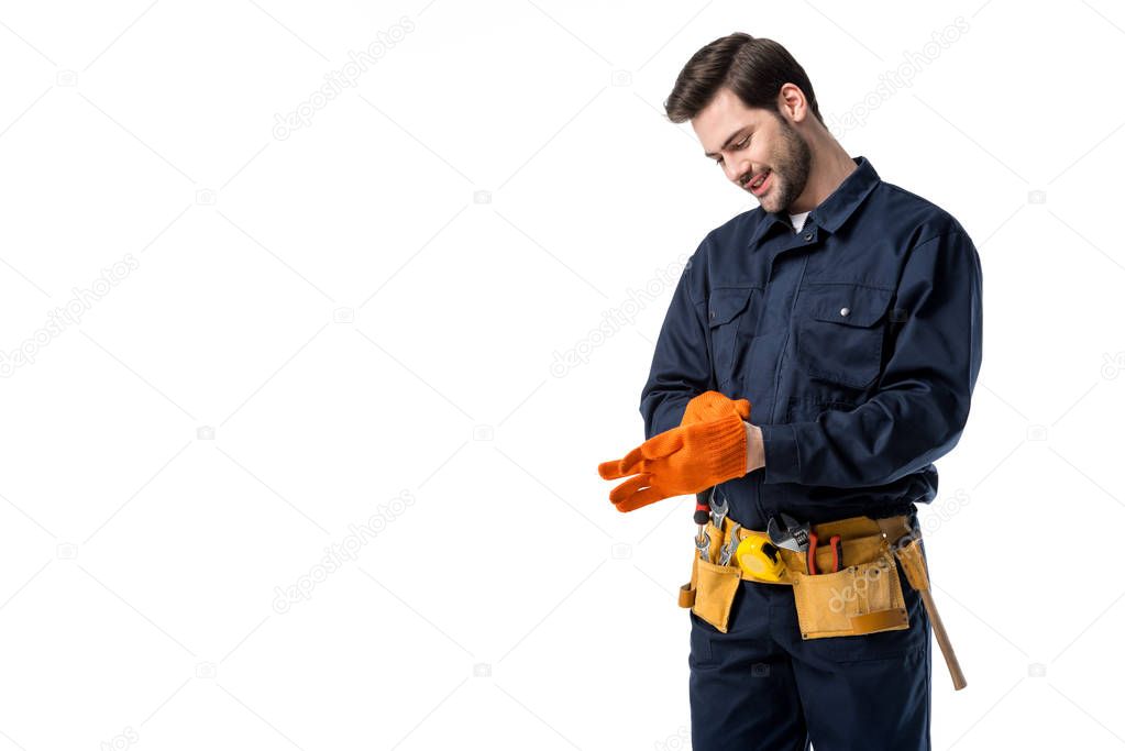 smiling plumber in uniform wearing protective gloves isolated on white