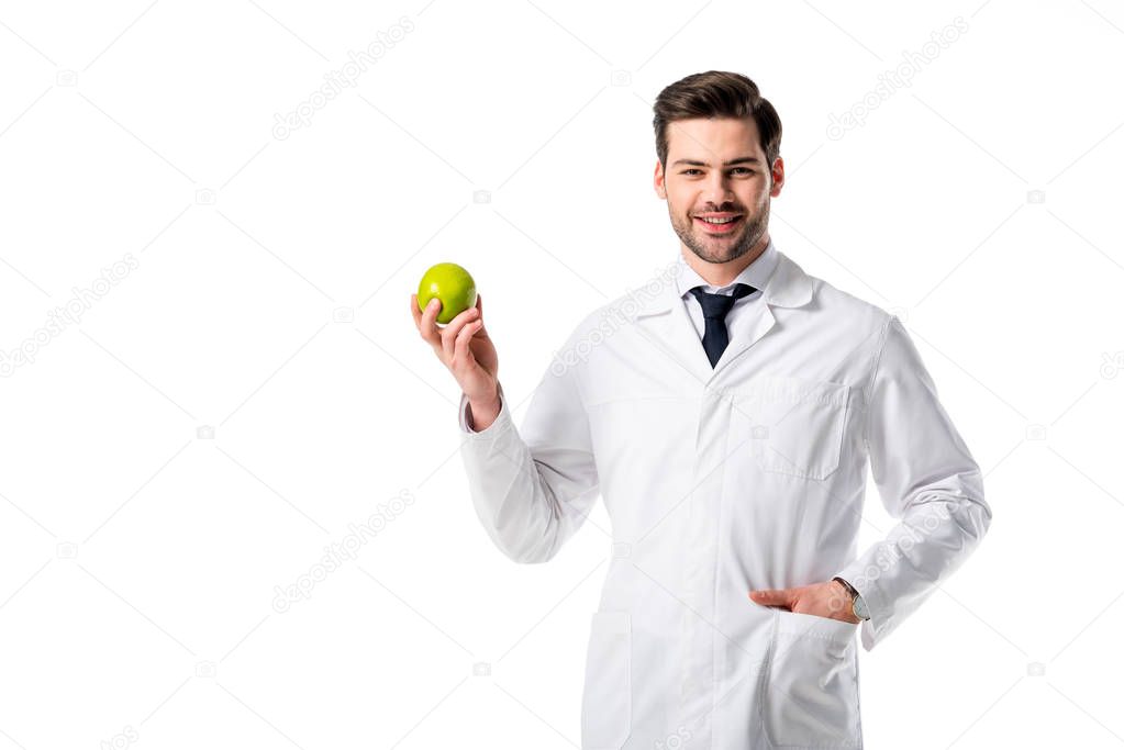 portrait of smiling nutritionist in white coat with fresh apple in hand isolated on white