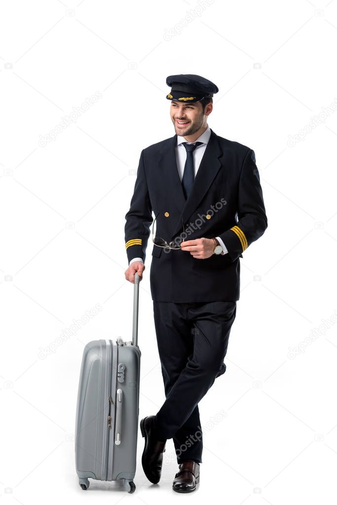 smiling pilot in uniform with luggage isolated on white